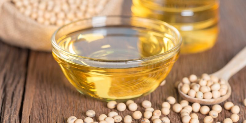 Soybean oil and Soybean on wooden table.